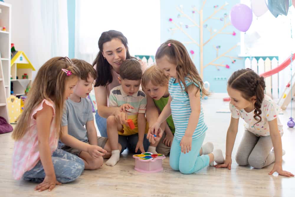 Female Teacher Teaching Kids Play Toy In Kindergarten